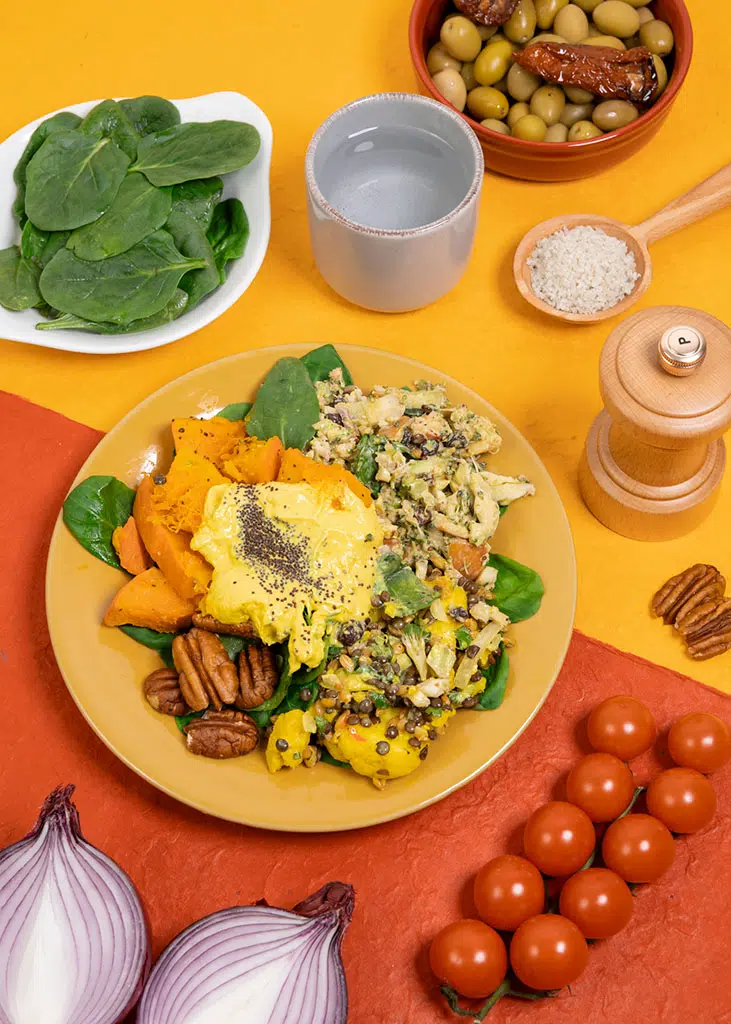 Food photography: summer mixed salad with squash, sweet potato, lentils, and avocado — colorfully arranged against a yellow and orange background, Paris
